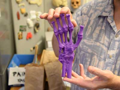 a v.c.u. student holds up a 3 dimensional printout of a hand skeleton