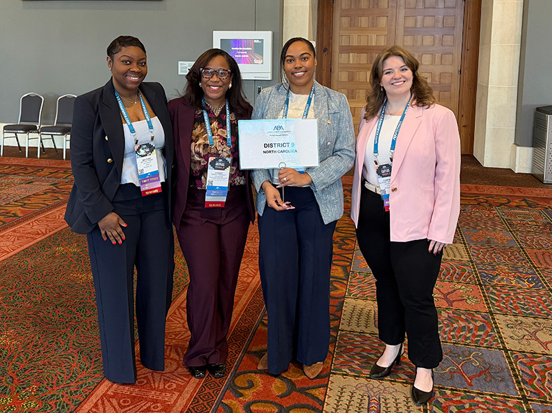 Courtney LaTourrette stands in a conference hall with with three other women