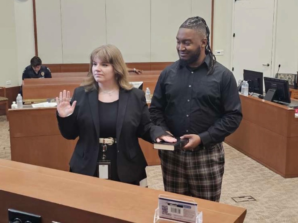 Courtney LaTourrette, standing in a courtroom beside a man holding a Bible, raising her right hand with her left hand on the Bible