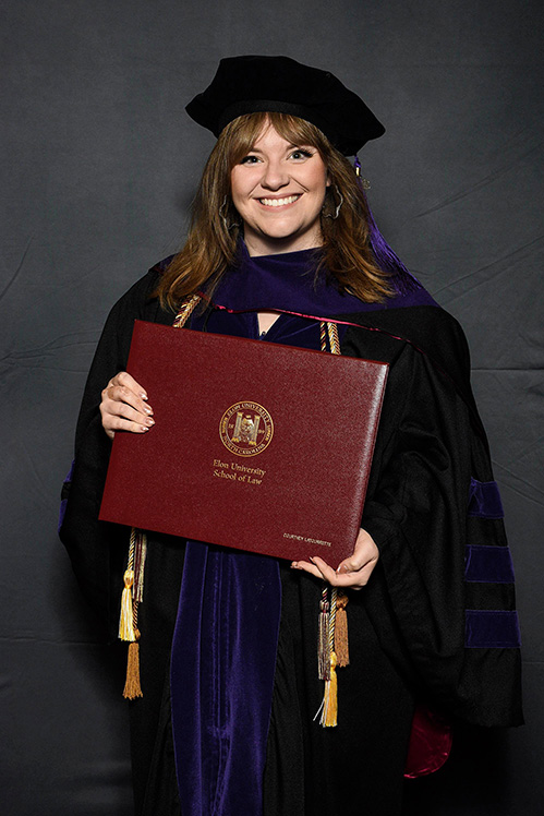 Courtney LaTourrette poses for a portrait in graduation regalia, holding a diploma