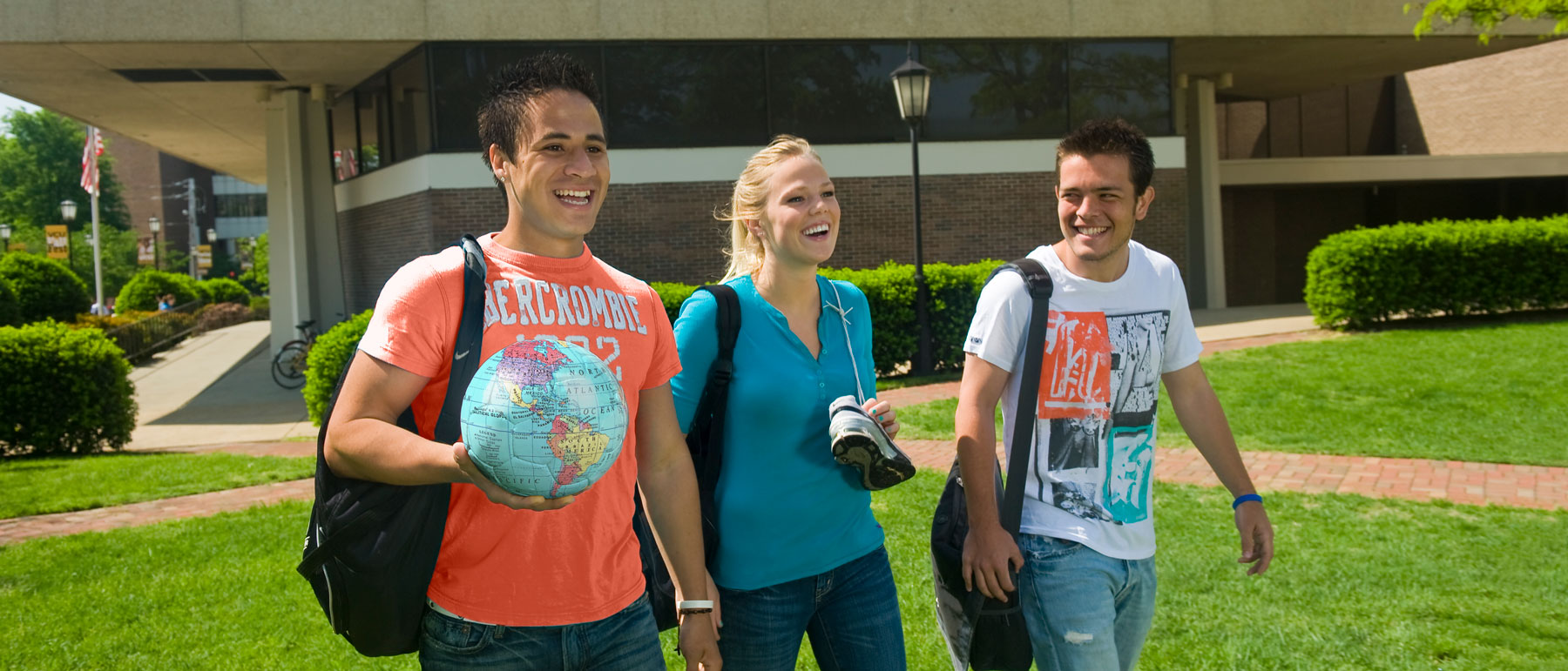 three v.c.u. students walking and laughing near harris hall with one of the three carrying a globe