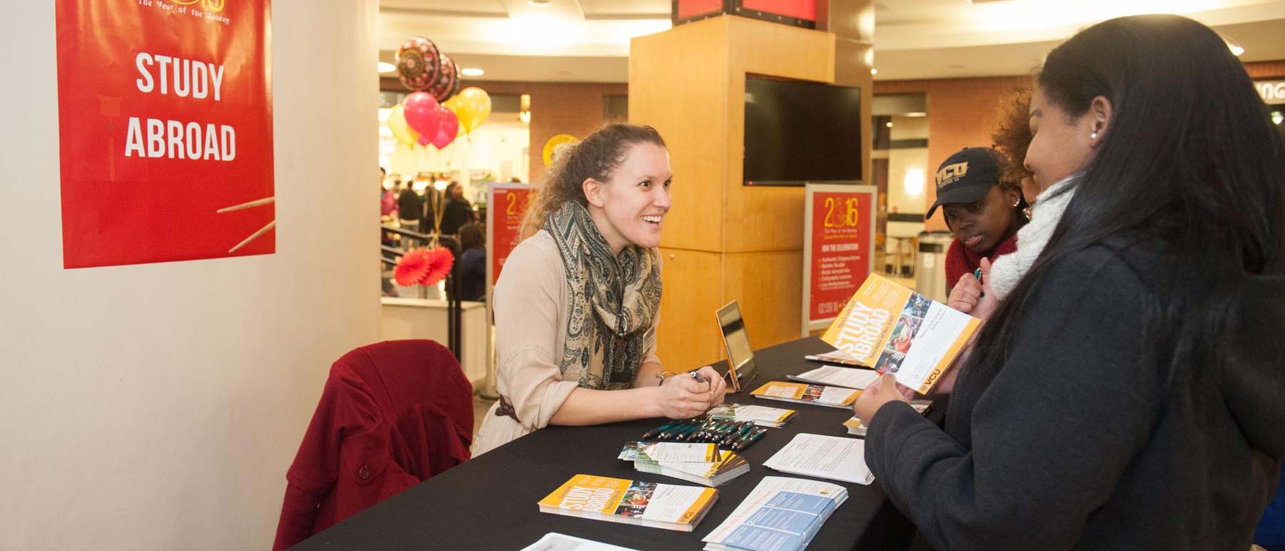 students talking to an adviser at a study abroad information table