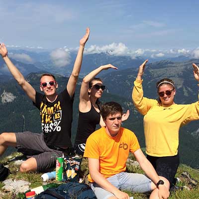 happy v.c.u. students in the mountains of austria creating the v.c.u. letters with their arms