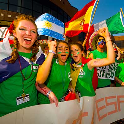 students, adorned with face paint, attending a parade while international flags fly the background