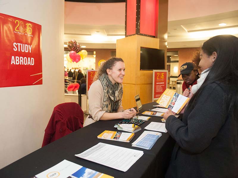 students talking to an adviser at a study abroad information table