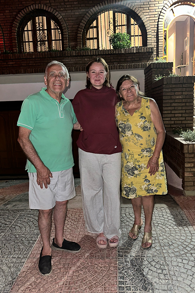 Eva Burcher standing with a man and woman on a patio in front of a brick building