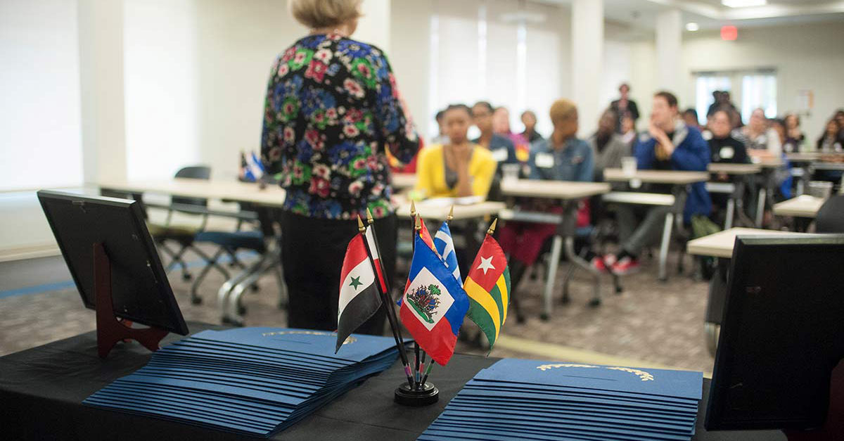 a table with booklets and international flags in the front of a classroom
